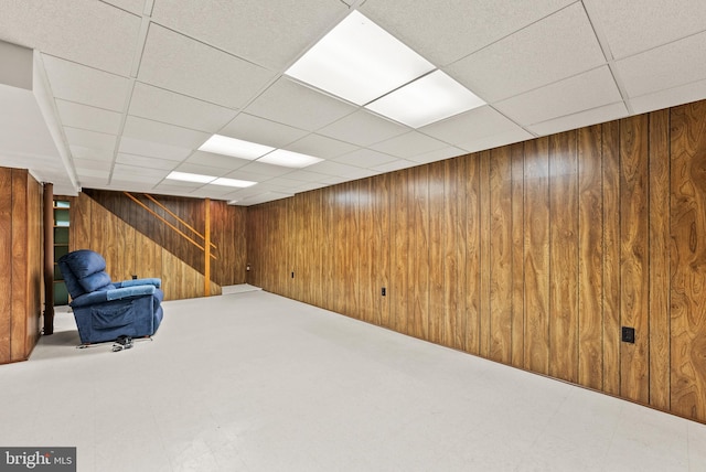 basement with wood walls and a drop ceiling