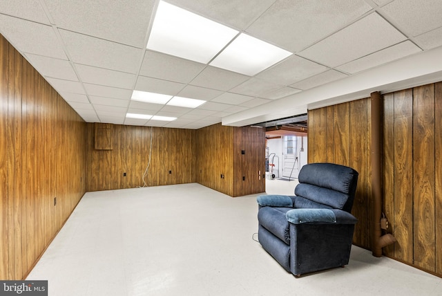 sitting room with a paneled ceiling and wooden walls