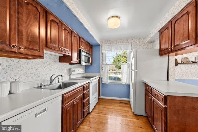 kitchen with sink, white appliances, and light wood-type flooring