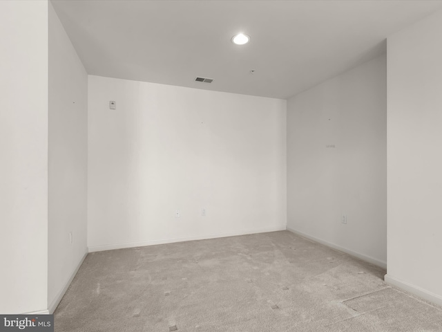 unfurnished room with carpet, visible vents, and baseboards