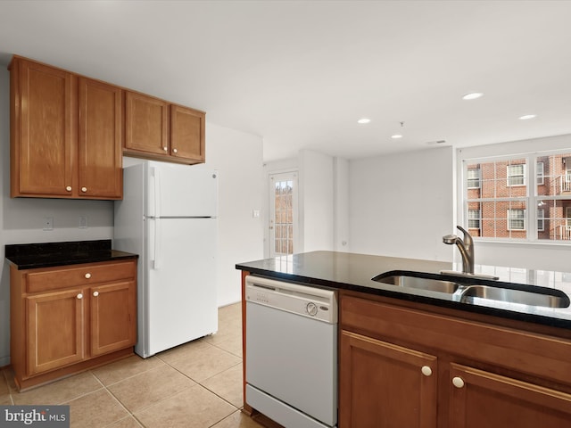 kitchen featuring white appliances, light tile patterned flooring, a sink, dark countertops, and brown cabinets