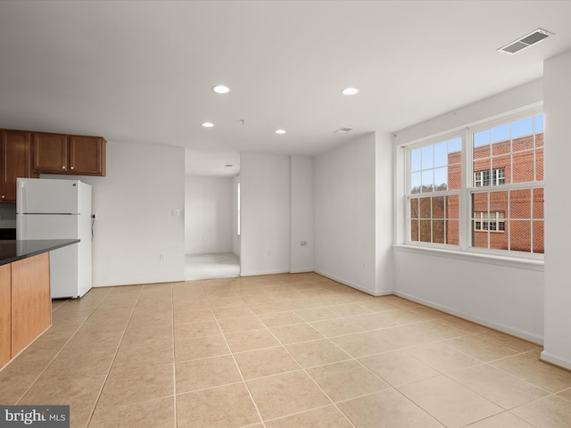 kitchen with visible vents, dark countertops, freestanding refrigerator, recessed lighting, and light tile patterned flooring