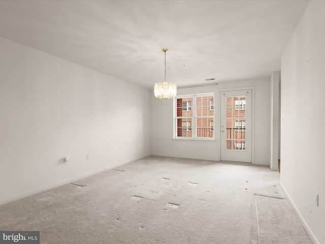 carpeted empty room with visible vents, baseboards, and a chandelier