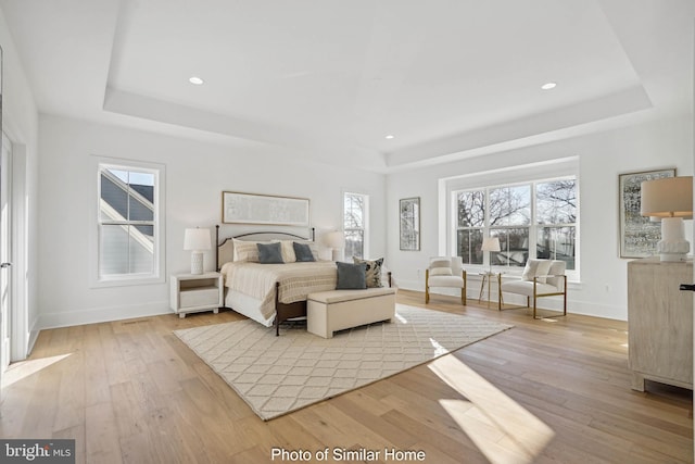 bedroom with light hardwood / wood-style flooring and a raised ceiling