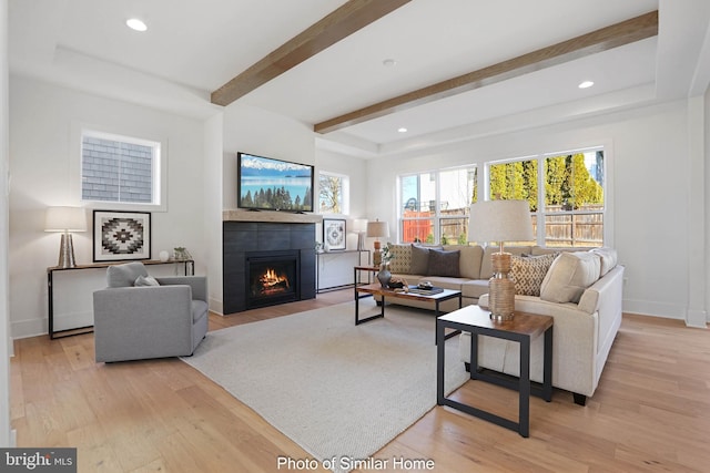 living room featuring a fireplace, beam ceiling, and light hardwood / wood-style flooring