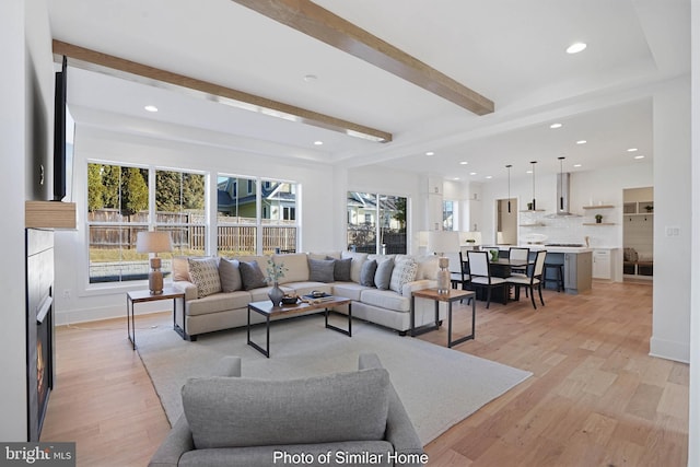 living room with beam ceiling, light hardwood / wood-style floors, and a wealth of natural light