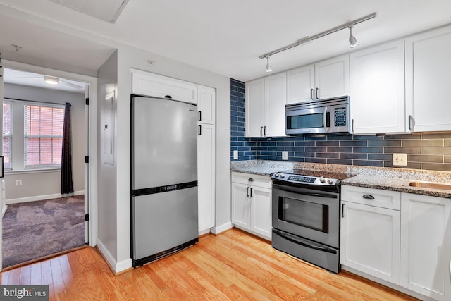 kitchen with decorative backsplash, appliances with stainless steel finishes, light hardwood / wood-style floors, and white cabinetry