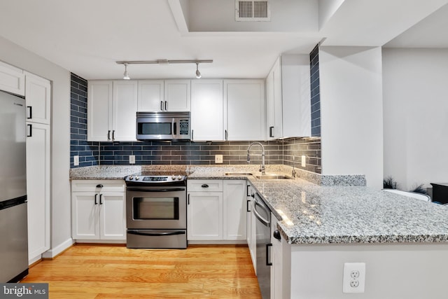 kitchen featuring light stone countertops, sink, light hardwood / wood-style flooring, white cabinets, and appliances with stainless steel finishes