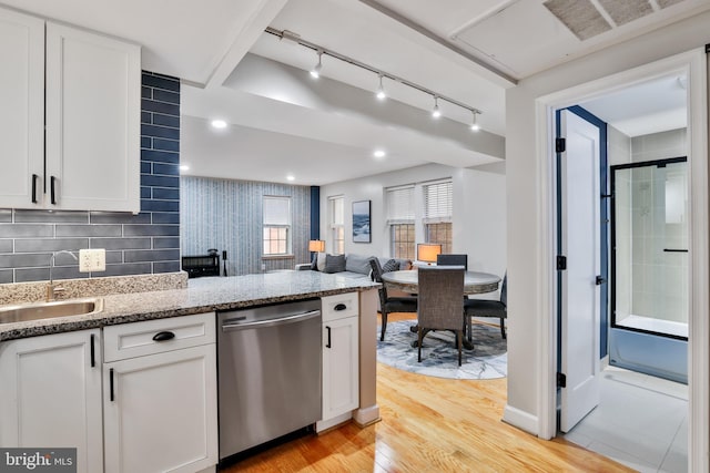 kitchen featuring sink, light stone counters, stainless steel dishwasher, white cabinets, and light wood-type flooring