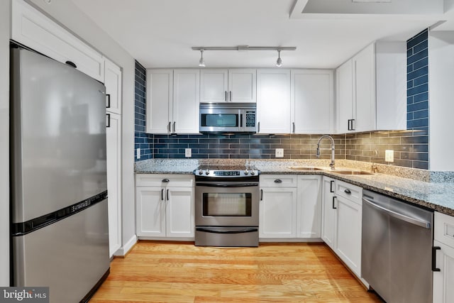 kitchen featuring light stone counters, stainless steel appliances, sink, light hardwood / wood-style flooring, and white cabinets