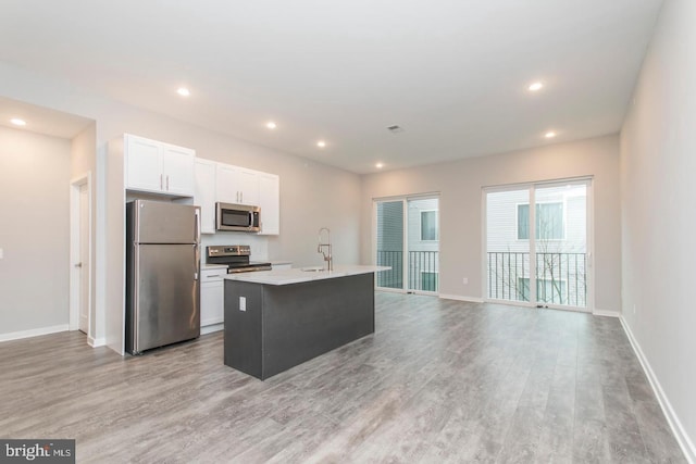 kitchen featuring white cabinetry, sink, light hardwood / wood-style flooring, a center island with sink, and appliances with stainless steel finishes