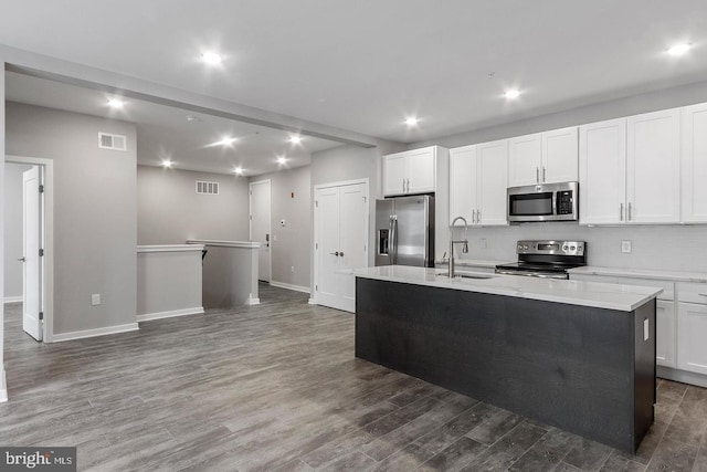 kitchen with stainless steel appliances, sink, dark hardwood / wood-style floors, white cabinetry, and an island with sink