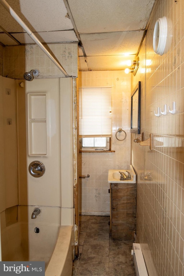 bathroom featuring a paneled ceiling, vanity, shower / bathtub combination, and tile walls