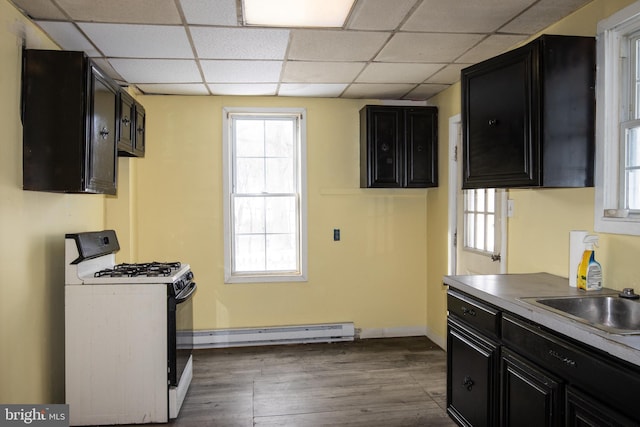 kitchen with dark hardwood / wood-style floors, baseboard heating, white gas stove, and sink