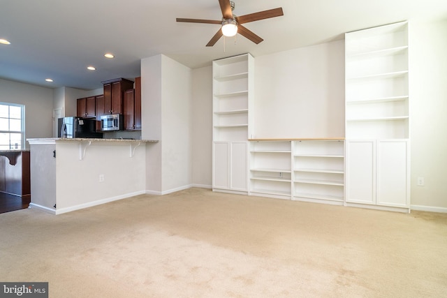 unfurnished living room featuring light carpet and ceiling fan