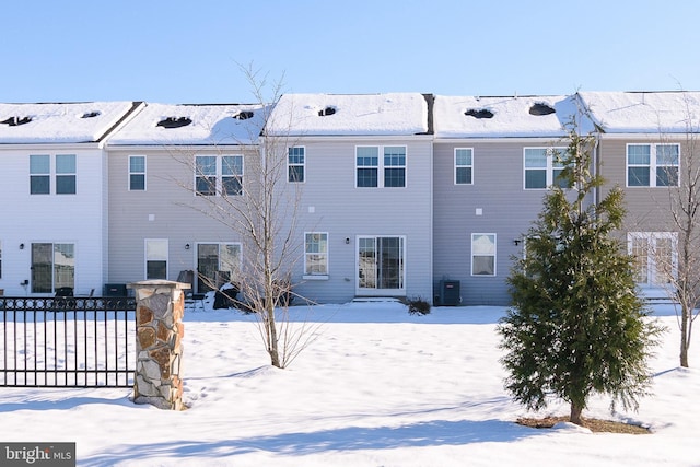 snow covered rear of property featuring central AC