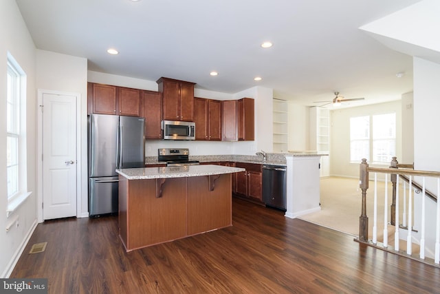 kitchen featuring light stone counters, ceiling fan, dark hardwood / wood-style floors, a breakfast bar, and appliances with stainless steel finishes