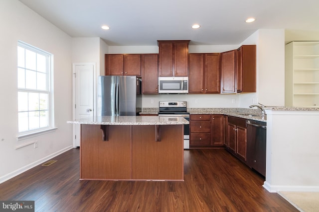 kitchen with appliances with stainless steel finishes, sink, a kitchen island, and dark hardwood / wood-style floors