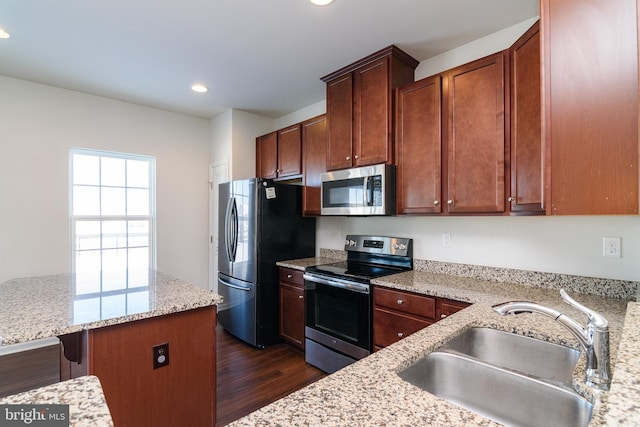 kitchen with stainless steel appliances, sink, a breakfast bar, and light stone counters