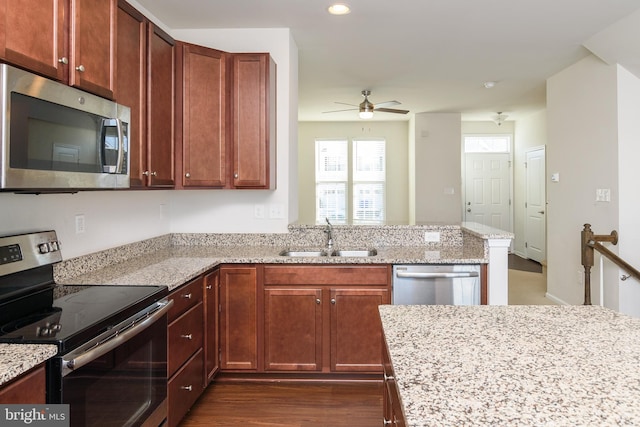 kitchen with sink, ceiling fan, light stone counters, and appliances with stainless steel finishes