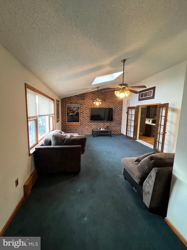 living room featuring ceiling fan, french doors, brick wall, lofted ceiling with skylight, and carpet