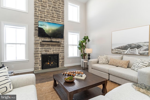 living room featuring hardwood / wood-style floors, a fireplace, and a high ceiling