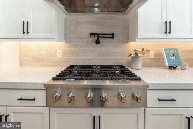 kitchen with backsplash, white cabinetry, stainless steel gas stovetop, and wall chimney exhaust hood