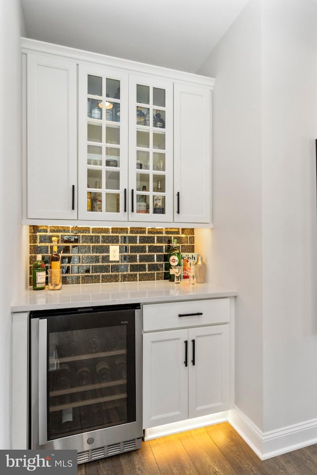 bar featuring backsplash, wine cooler, white cabinetry, and dark hardwood / wood-style flooring