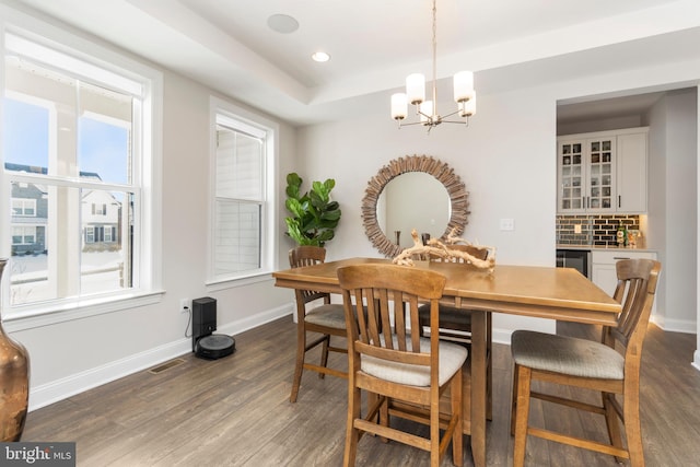 dining area with a notable chandelier, a healthy amount of sunlight, and dark hardwood / wood-style flooring