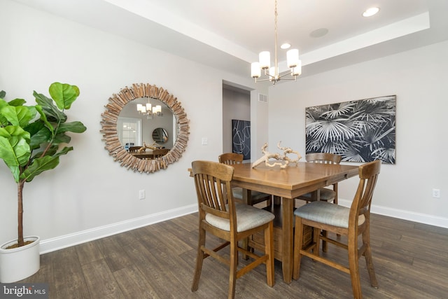 dining room with a chandelier, dark hardwood / wood-style flooring, and a raised ceiling