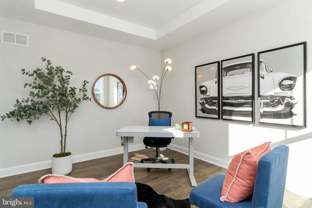 office space featuring a raised ceiling and dark wood-type flooring