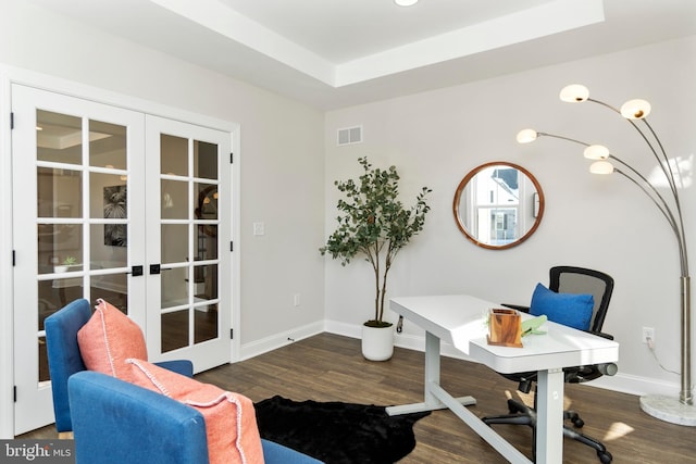 home office with a raised ceiling, dark wood-type flooring, and french doors