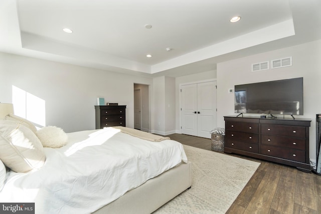 bedroom featuring dark hardwood / wood-style floors, a closet, and a tray ceiling