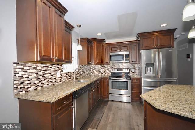 kitchen featuring light stone countertops, dark wood-type flooring, stainless steel appliances, decorative backsplash, and hanging light fixtures