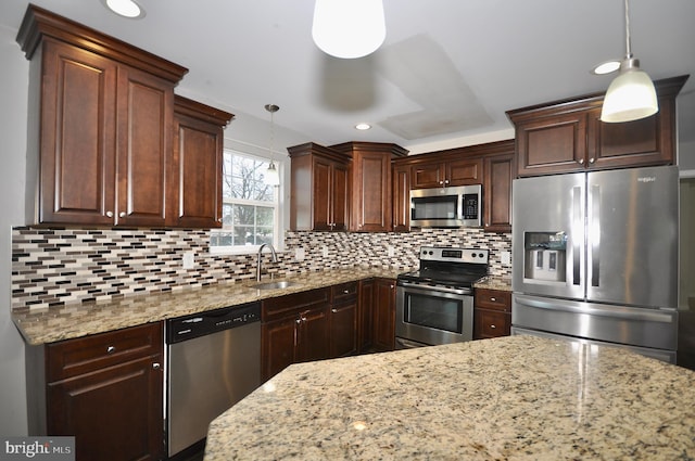 kitchen with stainless steel appliances, decorative backsplash, decorative light fixtures, light stone countertops, and sink