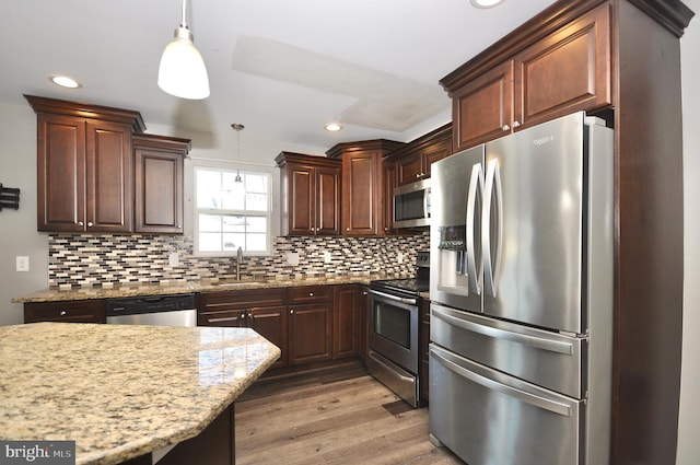 kitchen with stainless steel appliances, pendant lighting, and decorative backsplash