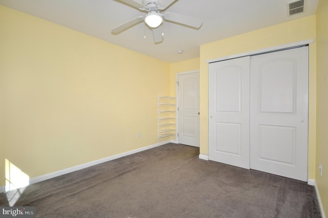 unfurnished bedroom featuring a closet, dark carpet, and ceiling fan