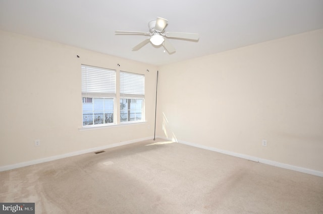 spare room with ceiling fan and light colored carpet