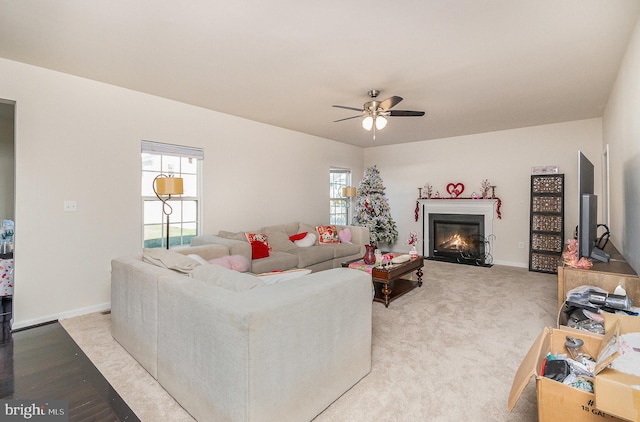 living room featuring a fireplace with flush hearth, plenty of natural light, baseboards, and a ceiling fan