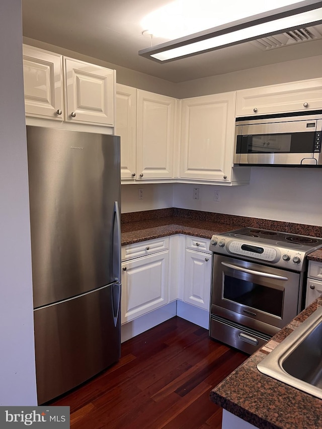 kitchen with dark hardwood / wood-style flooring, stainless steel appliances, and white cabinets