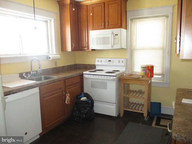 kitchen with white appliances, decorative light fixtures, and sink