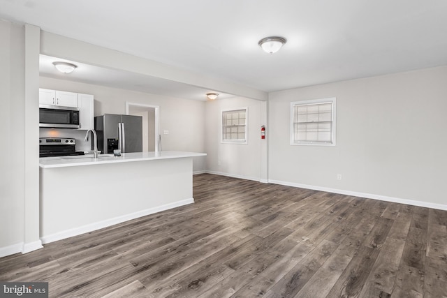 kitchen with sink, dark hardwood / wood-style flooring, kitchen peninsula, white cabinets, and appliances with stainless steel finishes