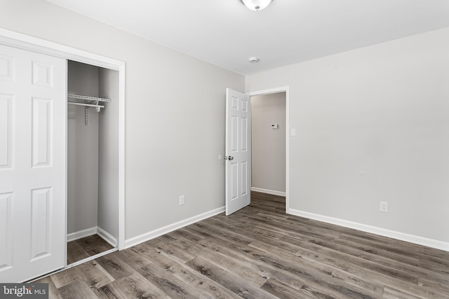 unfurnished bedroom with dark hardwood / wood-style flooring and a closet