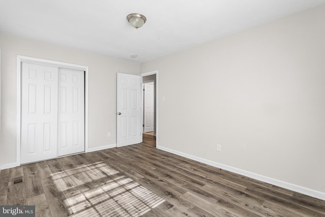 unfurnished bedroom featuring dark hardwood / wood-style floors and a closet