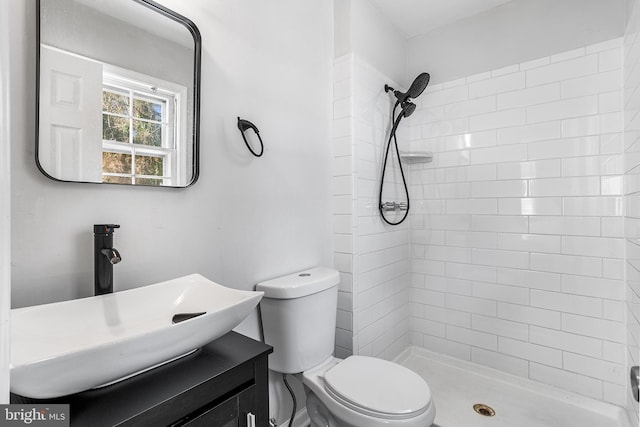 bathroom featuring vanity, toilet, and tiled shower