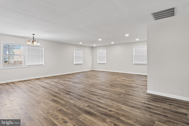 empty room featuring an inviting chandelier and dark wood-type flooring