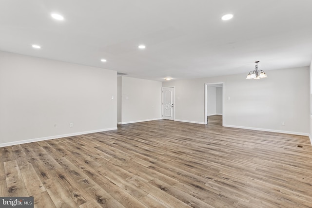 spare room with light hardwood / wood-style floors and an inviting chandelier