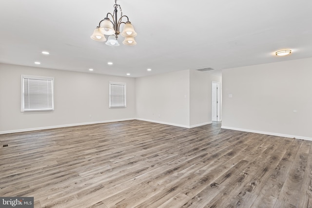 spare room featuring a notable chandelier and light hardwood / wood-style floors