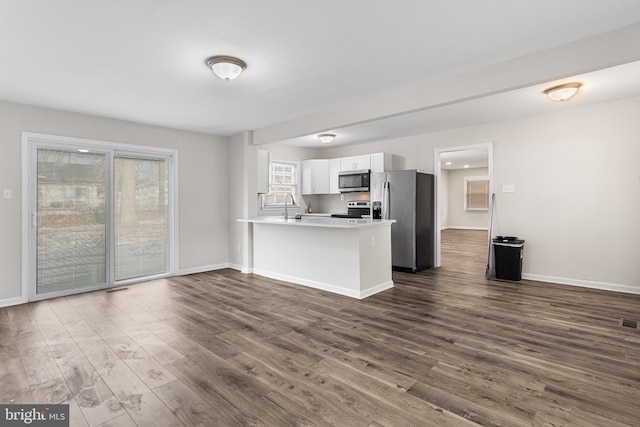 kitchen featuring kitchen peninsula, dark hardwood / wood-style flooring, stainless steel appliances, sink, and white cabinets