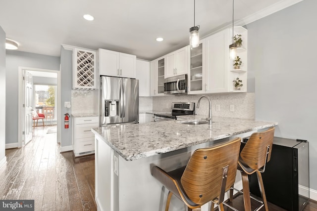 kitchen featuring white cabinetry, kitchen peninsula, pendant lighting, stainless steel appliances, and a breakfast bar area